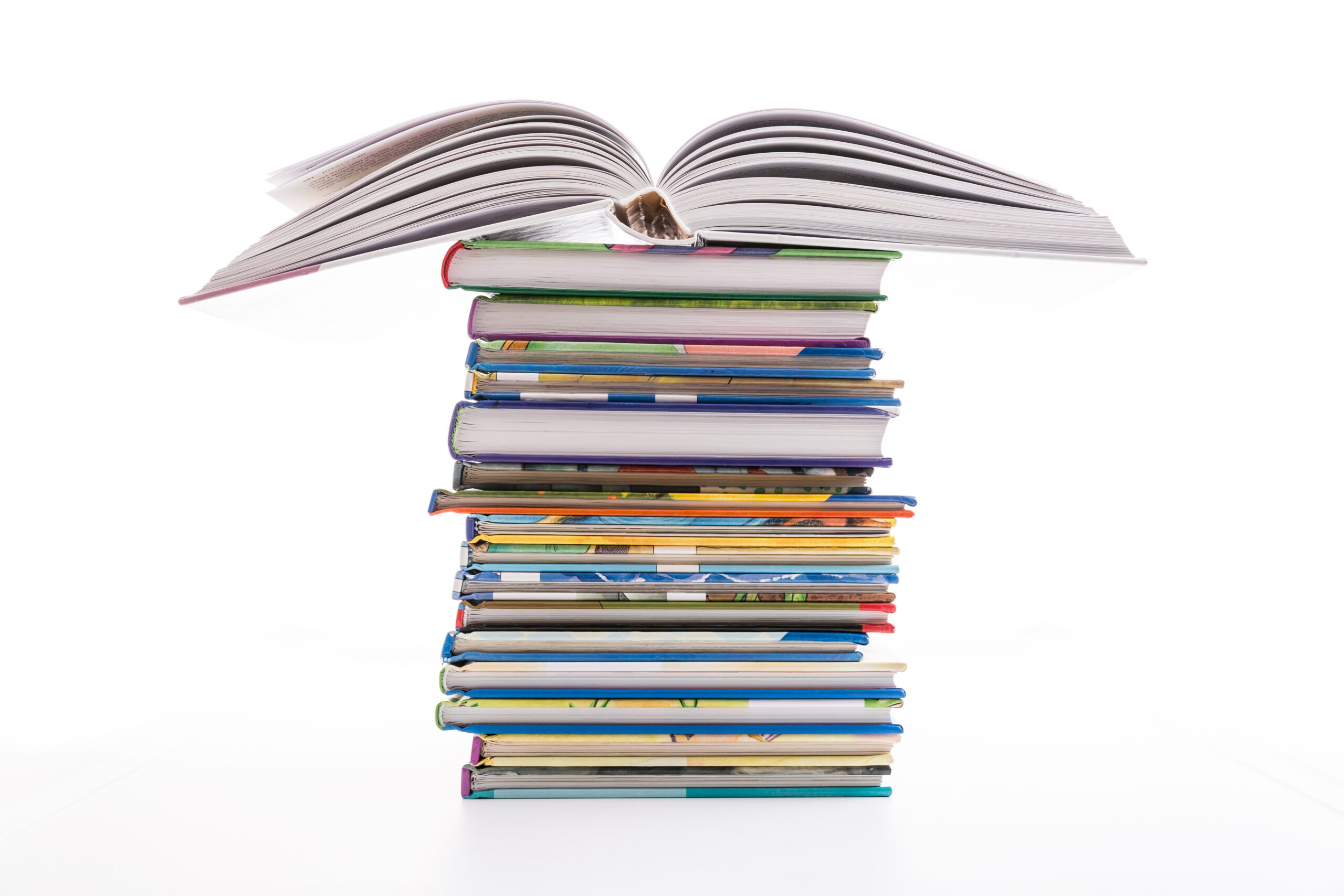 A stack of colorful hardcover books with an open book placed on top, all set against a white background.