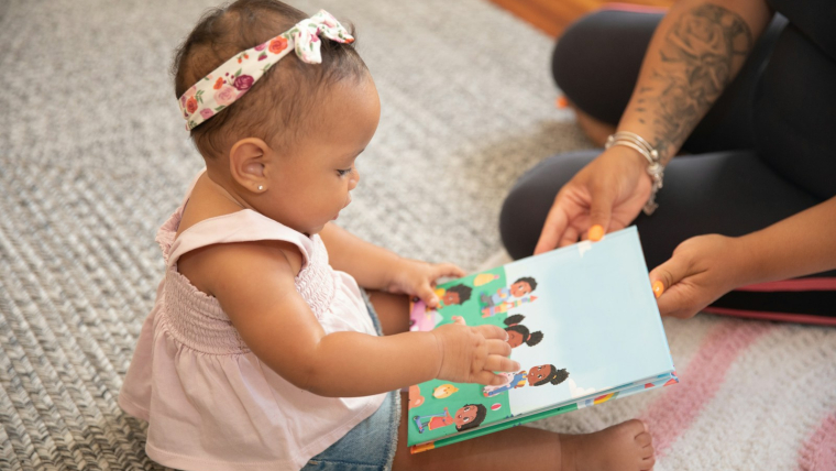 a baby sitting on the floor reading a book