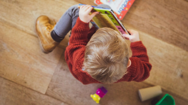 sitting toddler in red sweater holding book